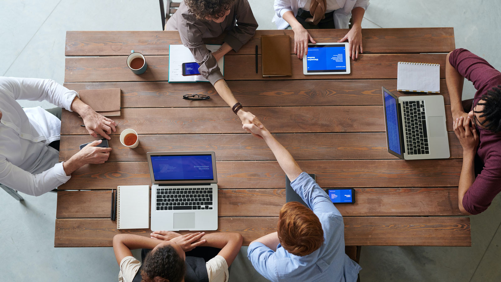 People shaking hands over table in conference room